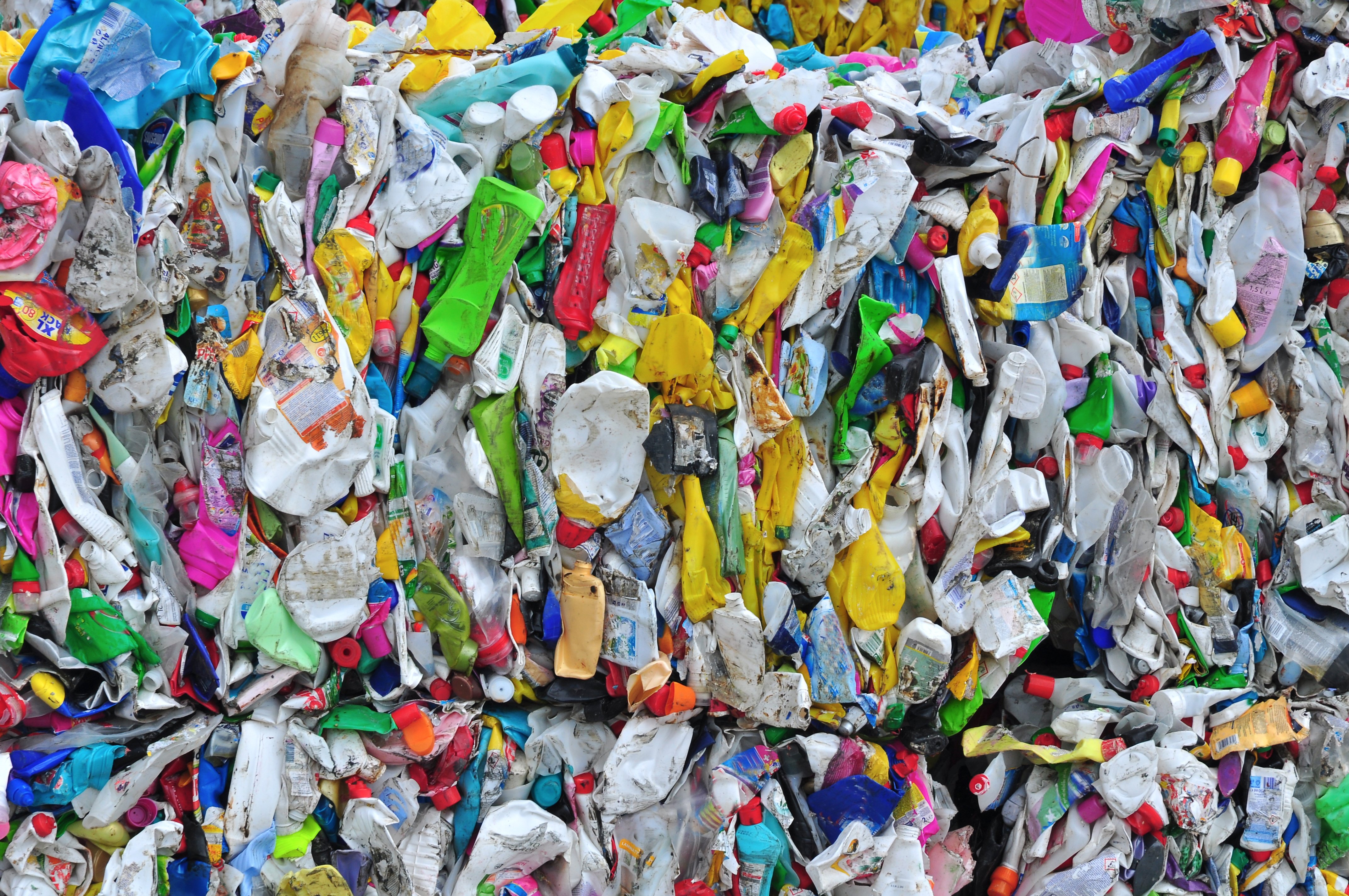 Bales of compressed plastic waste in various colors, including bottles and containers, representing recycling and environmental issues