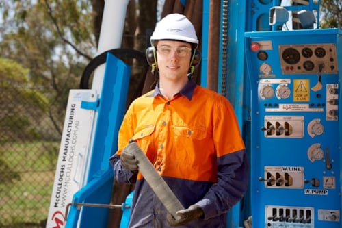 Kiwa auditor in safety gear holding a core sample next to drilling equipment outdoors