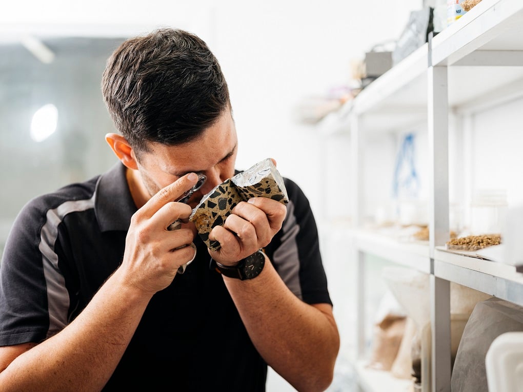 Kiwa KOAC laborary employee inspecting asphalt with a magnifying glass in a laboratory setting