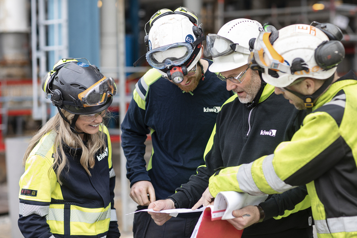 Group of Kiwa inspectors in safety gear reviewing blueprints on-site