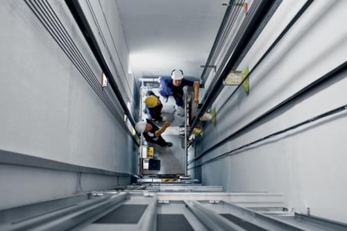 three employees doing an inspection of a lift