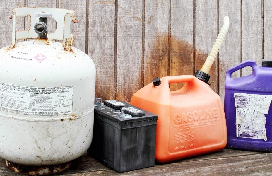 Behållare för kemikalier av olika slag: gasbehållare, bilbatteri, bensindunk och plastdunk för annan vätska.