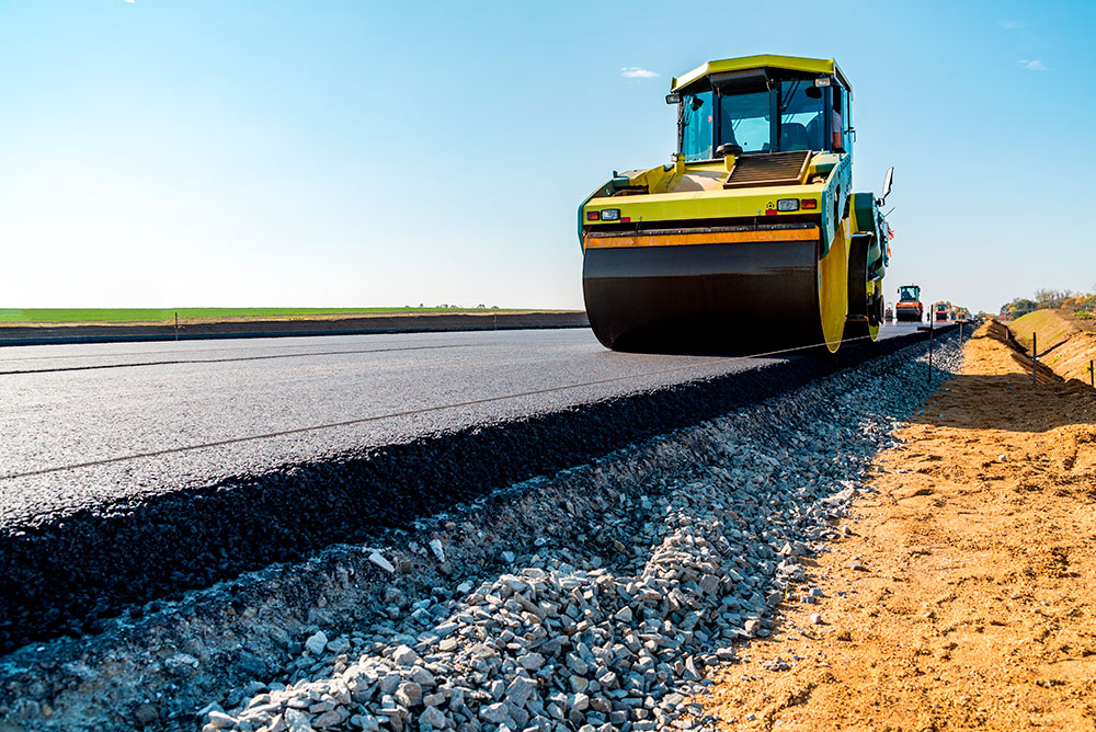 En vägvält körs på en nyasfalterad väg. 