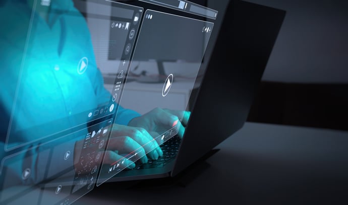 I skärmarna speglas en persons händer som skriver på ett tangentbord. 