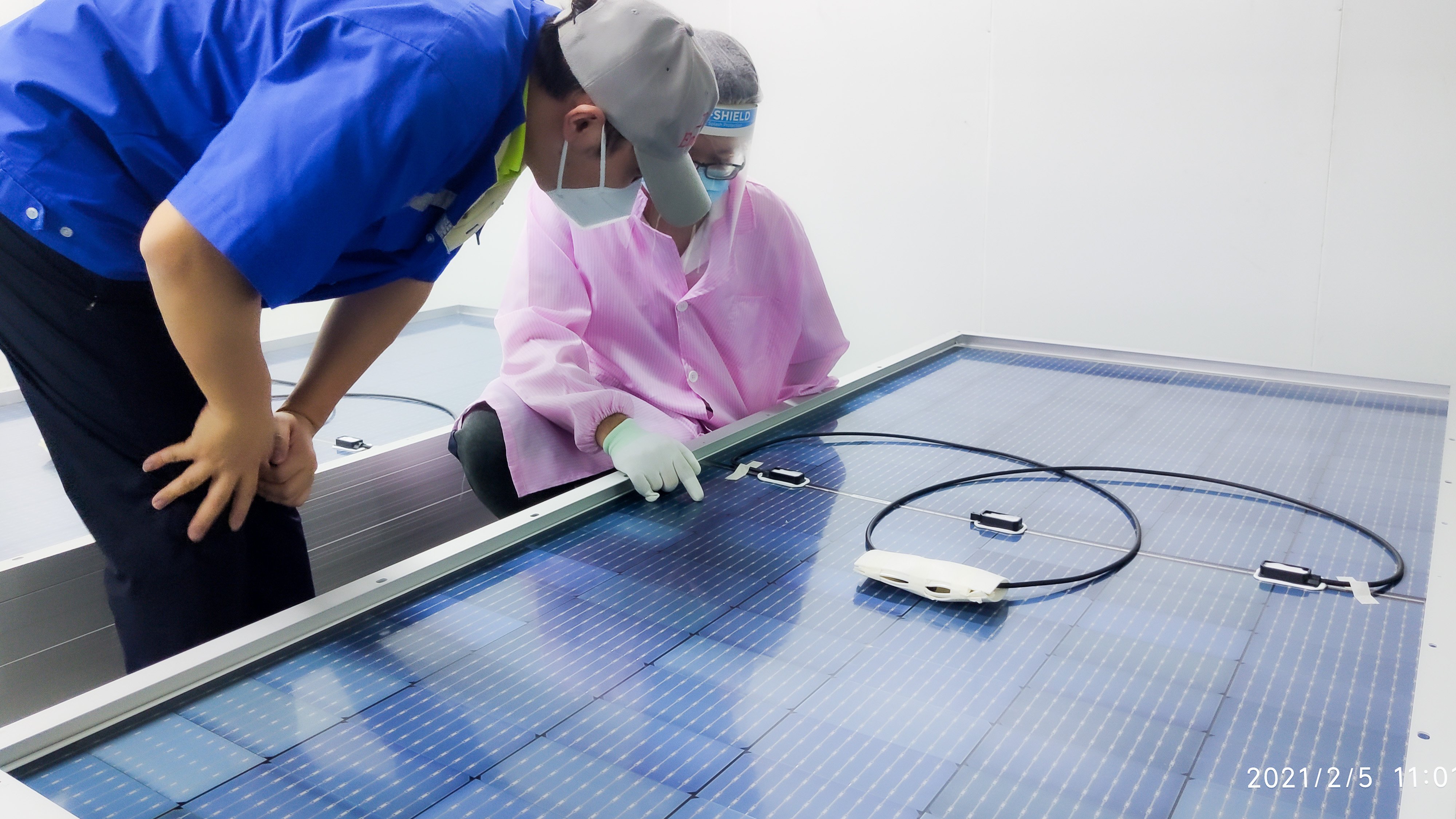 Kiwa PI Berlin auditors inspecting solar panel components in a cleanroom environment, highlighting quality control in solar energy production