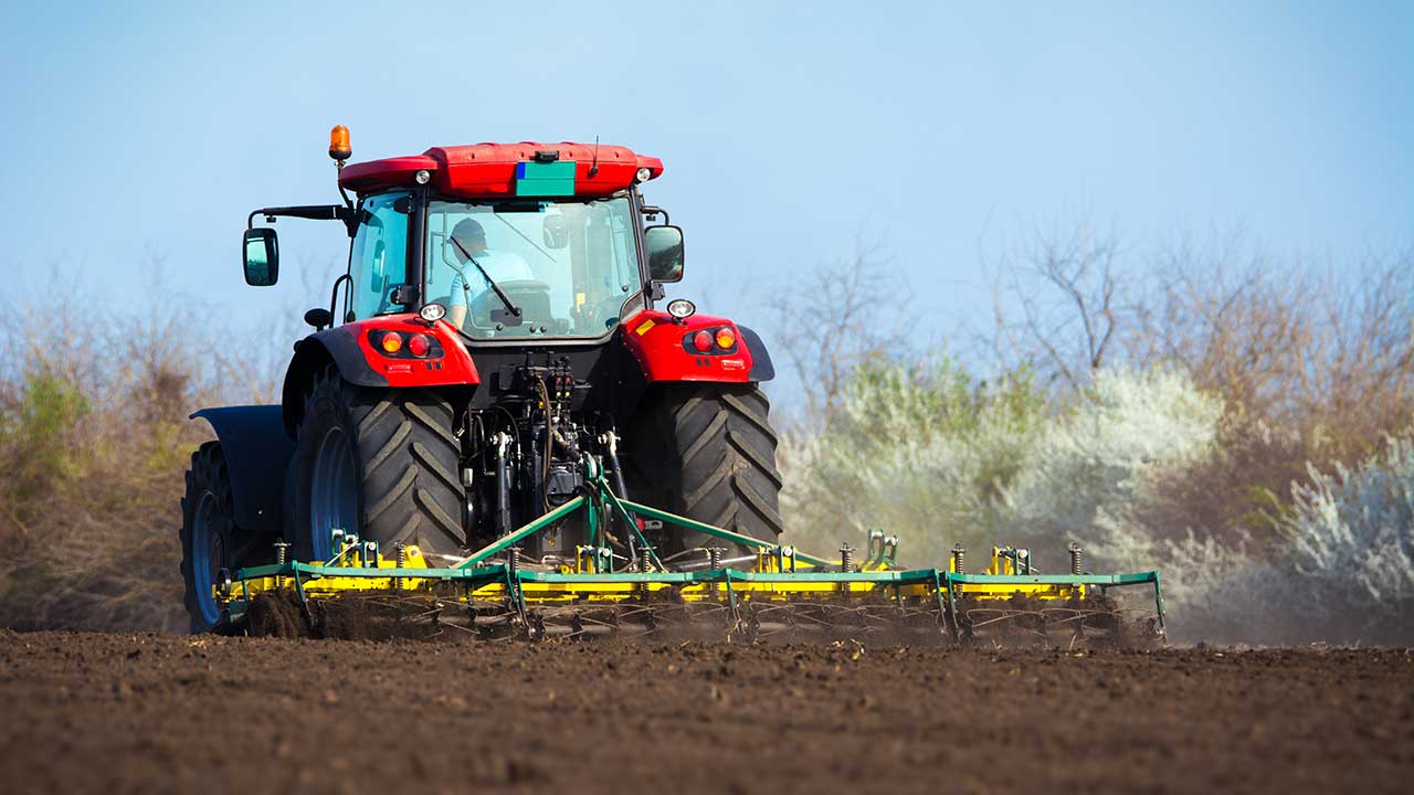 Traktor kör på åker