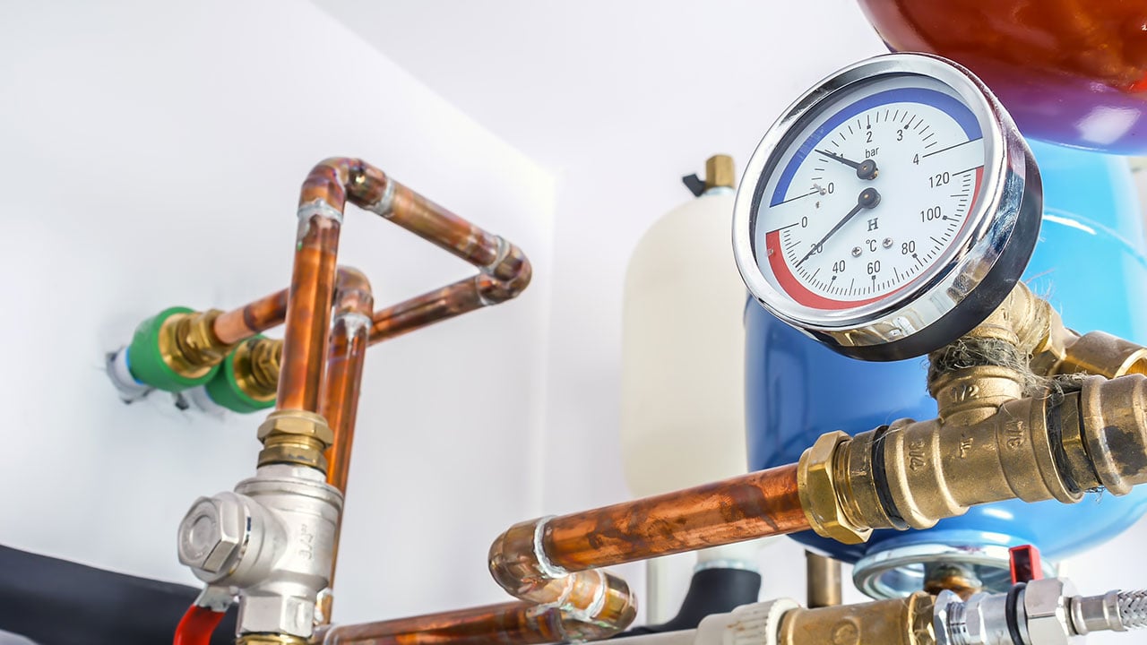 Rör, mätare och exansionskärl i en värmecentral för en fastighet. 