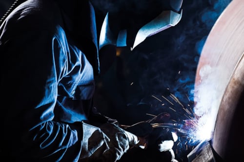 Svetsare svetsar på ett tryckkärl eller cisternliknande föremål.