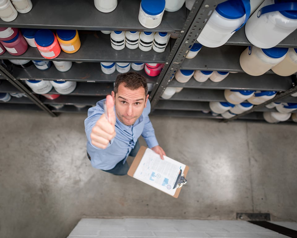 En man hanterar kemikaliehantering och kemikalies&auml;kerhet p&aring; ett lager visar tumme upp. 